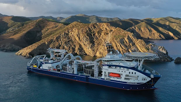 Cable-laying vessel at the Marinus Link landfall, moored beneath coastal ranges