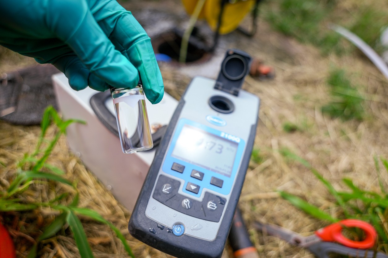 Field officer reading a water sample against a handheld turbidity meter